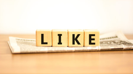 Like symbol. Concept word Like on beautiful wooden blocks on newspaper. Beautiful wooden table white...