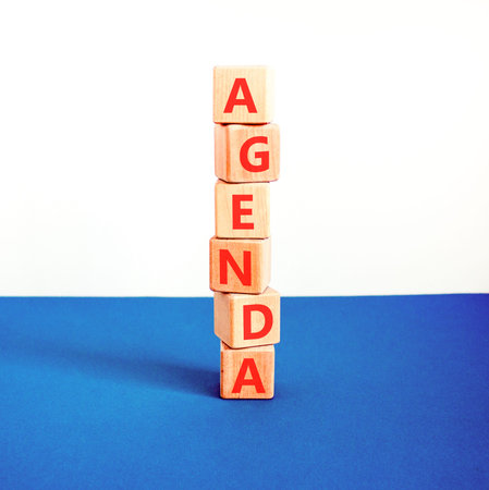 Agenda symbol. Concept word Agenda on beautiful wooden blocks. Beautiful blue and white background....