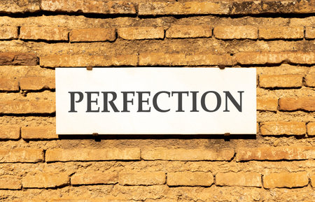 Perfection symbol. Concept word Perfection on beautiful white marble sign plate. Beautiful ancient brick wall background. Business perfection concept. Copy space.の写真素材