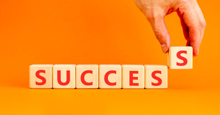 Successful success symbol. Concept word Success on beautiful wooden blocks. Beautiful orange background. Businessman's hand. Business success or successful concept. Copy space.の写真素材