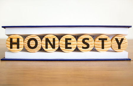 Honesty word symbol. Concept word Honesty on beautiful wooden circles in book. Beautiful wooden table white background. Business honesty concept. Copy space.の写真素材