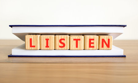 Listen symbol. Concept Listen word on beautiful wooden blocks in beautiful book. Beautiful wooden table white background. Business education listen concept. Copy space.の写真素材