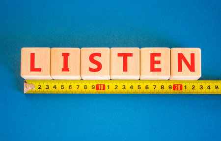 Listen symbol. Concept Listen word on beautiful wooden blocks. Beautiful blue background. Beautiful yellow tape measure ruler. Business education listen concept. Copy space.の写真素材