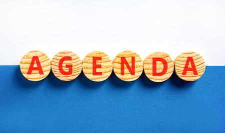 Agenda symbol. Concept word Agenda on beautiful wooden circles. Beautiful blue and white background. Business agenda concept. Copy space.の写真素材