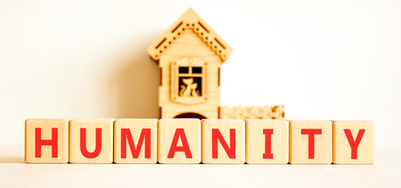 Humanity word symbol. Concept word Humanity on beautiful wooden blocks. Beautiful white background. Beautiful miniature wooden house. Copy space.の写真素材