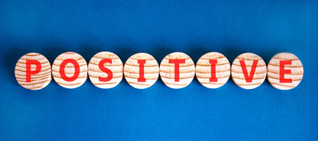 Positive word symbol. Concept word Positive on beautiful wooden circles. Beautiful blue background. Business support help positive word concept. Copy space.の写真素材