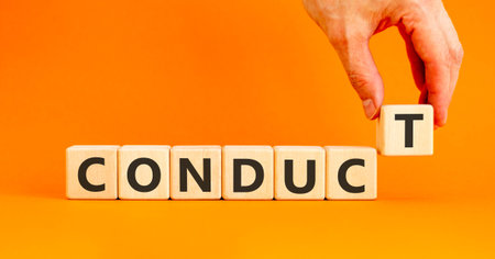 Conduct symbol. Concept word Conduct on beautiful wooden blocks. Beautiful orange background. Businessman's hand. Business conduct concept. Copy space.の写真素材