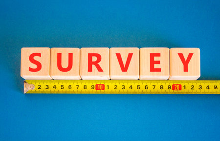 Survey word symbol. Concept word Survey on beautiful wooden blocks. Beautiful blue background. Beautiful yellow tape measure ruler. Business psychological medical survey word concept. Copy space.の写真素材