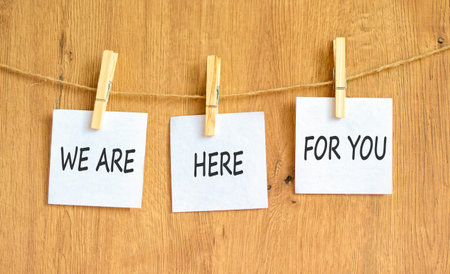 Support, help and we are here for you symbol. Concept words We are here for you on beautiful white papers on clothespin. Beautiful wooden background. Business we are here for you concept. Copy space.の写真素材