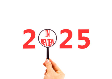 2025 in review new year symbol. Concept words 2025 in review in beautiful magnifying glass. Beautiful white background. Businessman's hand. Business 2025 in review new year concept. Copy space.の写真素材
