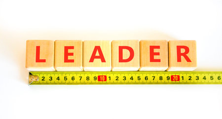 Leadership and leader symbol. Concept word Leader on beautiful wooden blocks. Beautiful white background. Beautiful yellow tape measure ruler. Business leader and leadership concept. Copy space.の写真素材