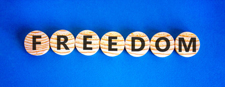 Freedom support symbol. Concept word Freedom on beautiful wooden circles. Beautiful blue background. Business freedom support concept. Copy space.の写真素材