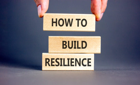 How to build resilience symbol. Concept words How to build resilience on beautiful wooden blocks. Beautiful gray background. Businessman's hand. Business how to build resilience concept. Copy spaceの写真素材