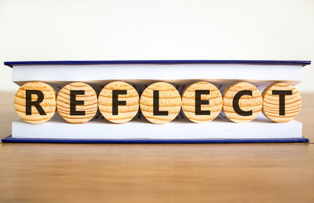 Reflect word symbol. Concept word Reflect on beautiful wooden circles in book. Beautiful wooden table white background. Business psychological reflect word concept. Copy space.の写真素材