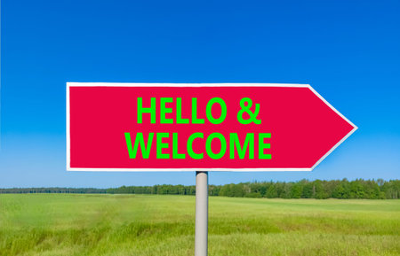 Hello and welcome symbol. Concept words Hello and welcome on beautiful red road sign. Beautiful blue sky green grass field background. Business hello and welcome concept. Copy space.の写真素材