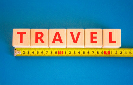 Travel traveling touristic symbol. Concept word Travel on beautiful blocks. Beautiful blue background. Beautiful yellow tape measure ruler. Business travel traveling touristic word concept Copy spaceの写真素材
