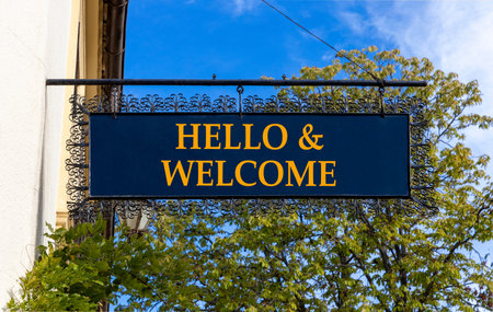 Hello and welcome symbol. Concept words Hello and welcome on beautiful big black road sign. Beautiful blue sky green trees background. Business hello and welcome concept. Copy space.の写真素材