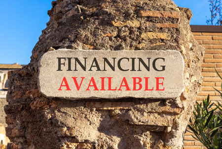 Financing available symbol. Concept words Financing available on beautiful big white sign plate. Beautiful old brown brick wall blue sky background. Business financing available concept. Copy space.の写真素材