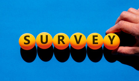 Survey word symbol. Concept word Survey on beautiful orange table tennis ping pong balls. Beautiful blue background. Psychologist's hand. Business psychological medical survey word concept. Copy spaceの写真素材