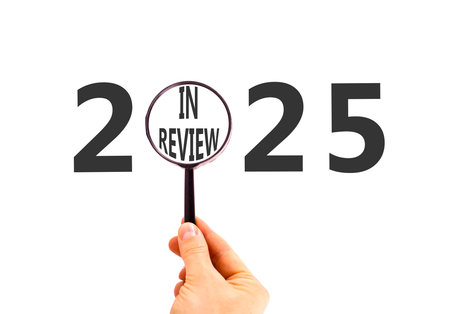 2025 in review new year symbol. Concept words 2025 in review in beautiful magnifying glass. Beautiful white background. Businessman's hand. Business 2025 in review new year concept. Copy space.の写真素材