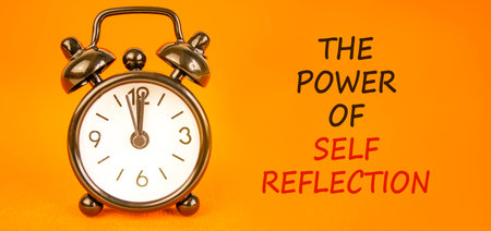 Self reflection symbol. Concept words The power of self reflection on beautiful orange paper. Beautiful orange background. Black alarm clock. Business the power of self reflection concept. Copy space.の写真素材
