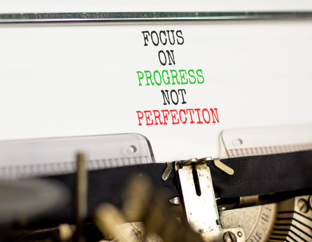 Progress or perfection words symbol. Concept words Focus on progress not perfection typed on old retro typewriter. Beautiful white background. Business progress or perfection concept. Copy space.の写真素材