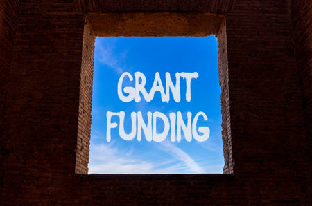 Grant funding symbol. Concept words Grant funding on beautiful blue sky in window in ancient wall....