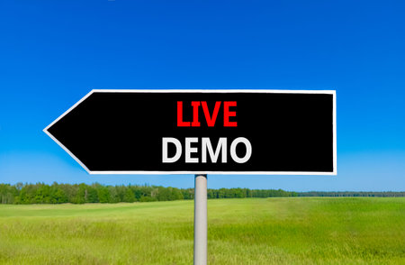 Live demo symbol. Concept words Live demo on beautiful black road sign. Beautiful blue sky green...