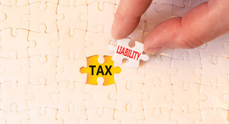 Tax liability words symbol. Concept words Tax liability on beautiful white puzzles. Beautiful yellow...