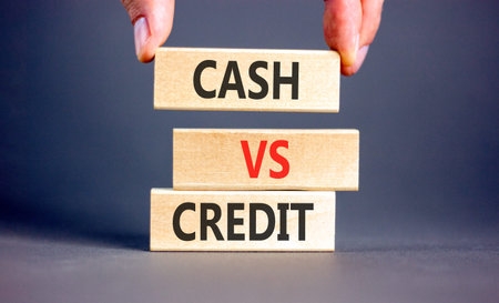 Cash vs credit words symbol. Concept words Cash vs credit on beautiful wooden blocks. Beautiful grey background. Businessman hand. Business and cash vs credit concept. Copy space.