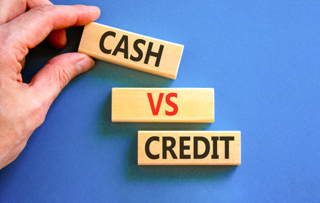 Cash vs credit words symbol. Concept words Cash vs credit on beautiful wooden blocks. Beautiful blue background. Businessman hand. Business and cash vs credit concept. Copy space.