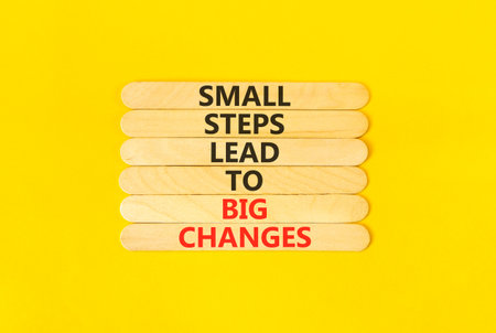 Small steps big changes words symbol. Concept words Small steps lead to big changes on beautiful wooden sticks. Beautiful yellow background. Business small steps big changes concept. Copy space.