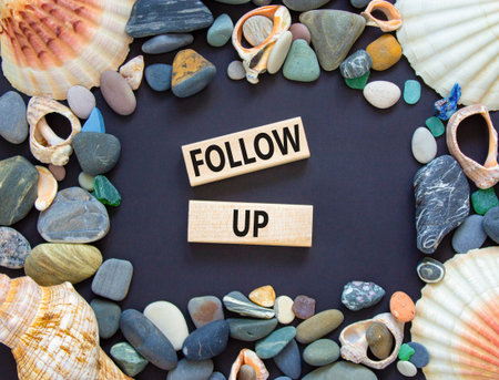 Follow up symbol. Concept word Follow up on beautiful wooden blocks. Beautiful black paper background. Beautiful sea stones and sea shells. Business follow up concept. Copy space.