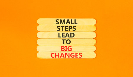 Small steps big changes words symbol. Concept words Small steps lead to big changes on beautiful wooden sticks. Beautiful orange background. Business small steps big changes concept. Copy space.