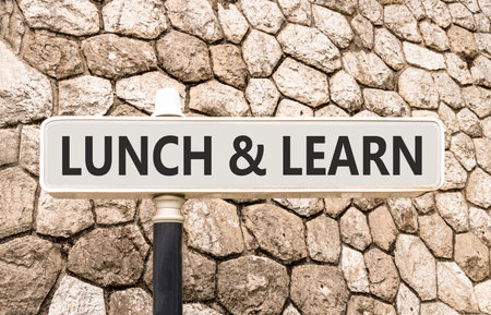 Lunch and learn symbol. Concept words Lunch and learn on beautiful big white road sign. Beautiful grey stone wall background. Business, educational and lunch and learn concept. Copy space.