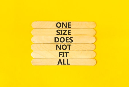 One size does not fit all symbol. Concept words One size does not fit all on wooden stick. Beautiful yellow table yellow background. One size does not fit all business concept. Copy space.