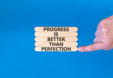 Progress or perfection words symbol. Concept words Progress is better than perfection on beautiful wooden sticks. Beautiful blue paper background. Business progress or perfection concept. Copy space