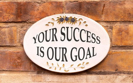 Your success is our goal symbol. Concept words Your success is our goal on white sign plate. Beautiful brick wall background. Business Your success is our goal concept. Copy space.