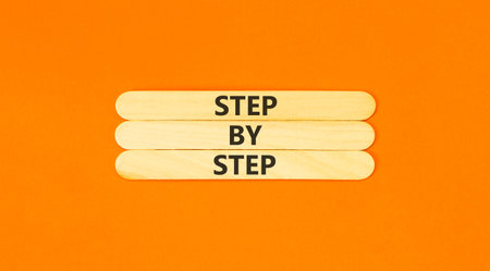 Next step words symbol. Concept words Step by step on beautiful wooden sticks. Beautiful orange background. Business and next step concept. Copy space.