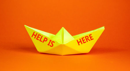 Help is here and support words symbol. Concept words Help is here on beautiful yellow paper boat. Beautiful orange background. Business help is here and support concept. Copy space.