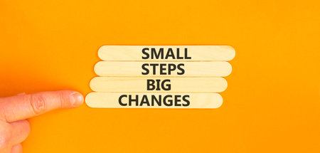 Small steps big changes words symbol. Concept words Small steps big changes on beautiful wooden sticks. Beautiful orange background. Business motivational small steps big changes concept. Copy space.