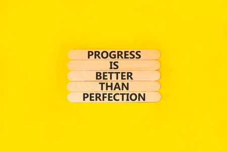 Progress or perfection words symbol. Concept words Progress is better than perfection on beautiful wooden sticks. Beautiful yellow paper background. Business progress or perfection concept. Copy space