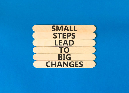 Small steps big changes words symbol. Concept words Small steps lead to big changes on beautiful wooden sticks. Beautiful blue background. Business small steps big changes concept. Copy space.