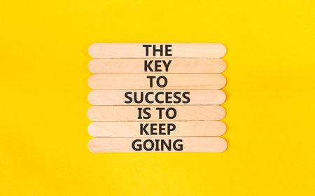 Success and keep going symbol. Concept words The key to success is to keep going on beautiful wooden sticks. Beautiful yellow paper background. Business success and keep going concept. Copy space.