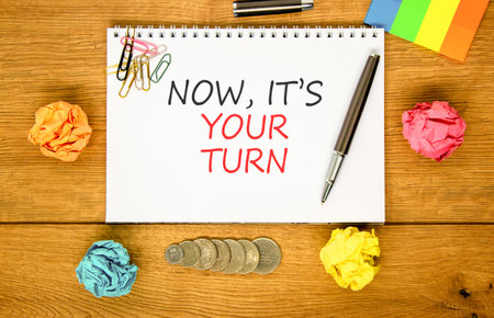 Now it's your turn symbol. Concept words Now it's your turn on beautiful white note. Beautiful wooden background. Colored paper. Business Now it's your turn motivational support concept. Copy space