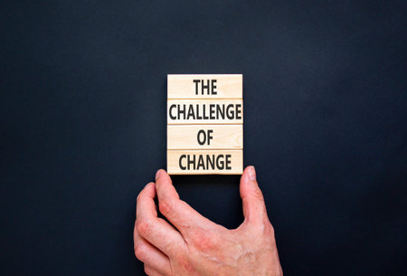 The challenge of change symbol. Concept words The challenge of change on beautiful wooden blocks. Beautiful black background. Businessman hand. Business the challenge of change concept. Copy space.