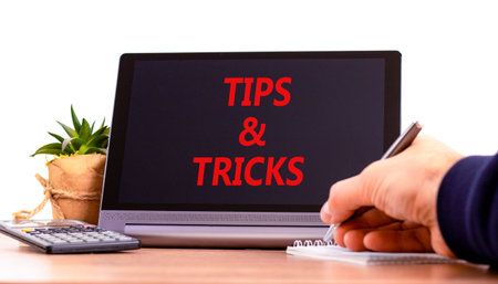 Tips and tricks words symbol. Concept words Tips and tricks on beautiful black tablet. Beautiful white background. Businessman hand. Business tips and tricks motivational support concept. Copy space.