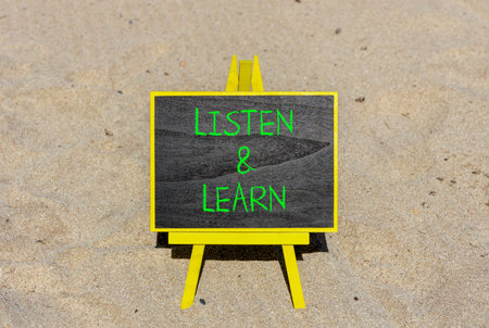 Listen and learn words symbol. Concept words Listen and learn on beautiful black blackboard. Beautiful sand beach background. Business listen and learn support concept. Copy space.