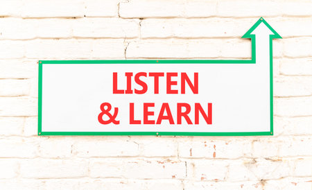 Listen and learn words symbol. Concept words Listen and learn on beautiful white sign plate. Beautiful white brick wall background. Business listen and learn support concept. Copy space.