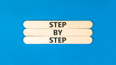 Next step words symbol. Concept words Step by step on beautiful wooden sticks. Beautiful blue background. Business and next step concept. Copy space.
